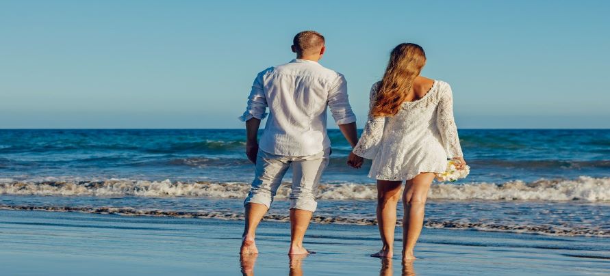 Pareja cogidos de la mano, de pie a la orilla del mar